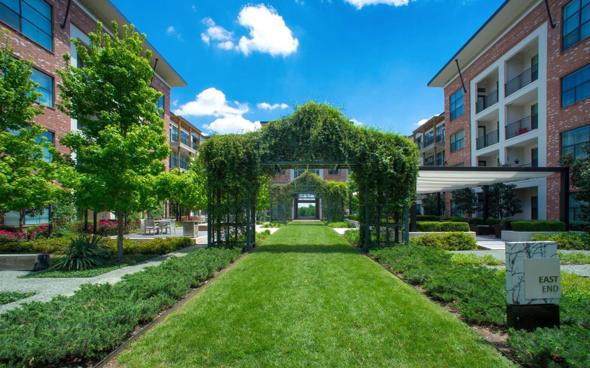 a courtyard with a green lawn and an ivy covered archway at Gramercy on the Park, Dallas, TX, 75287